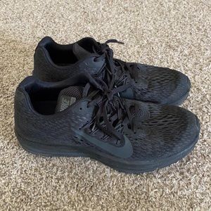 Solid black Nike zoom tennis shoe.